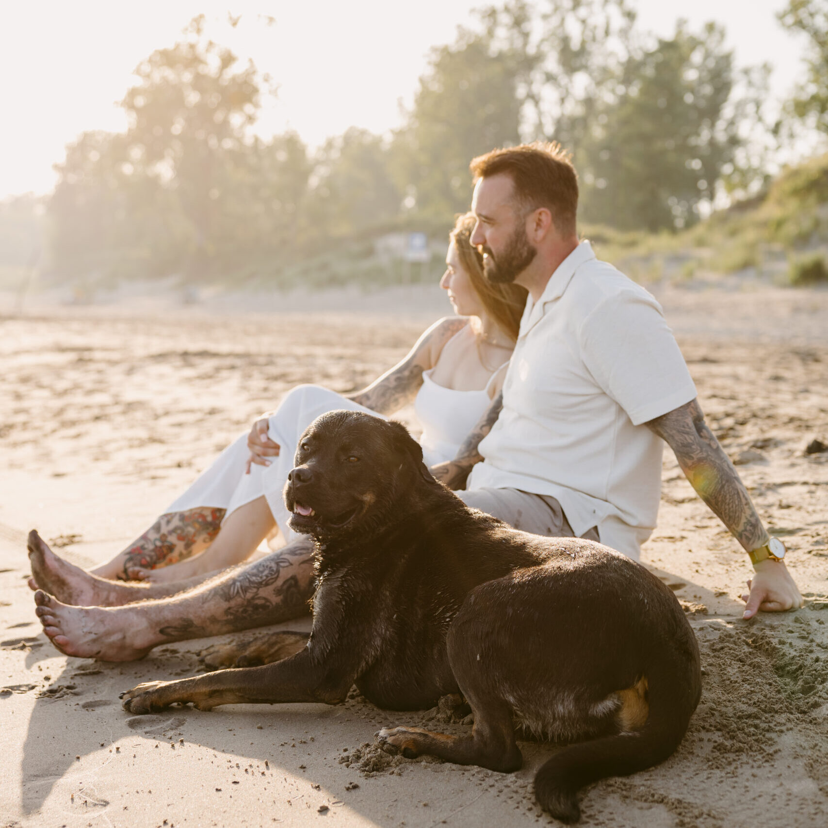 Couple running barefoot across Long Point Beach at sunset with their dog.