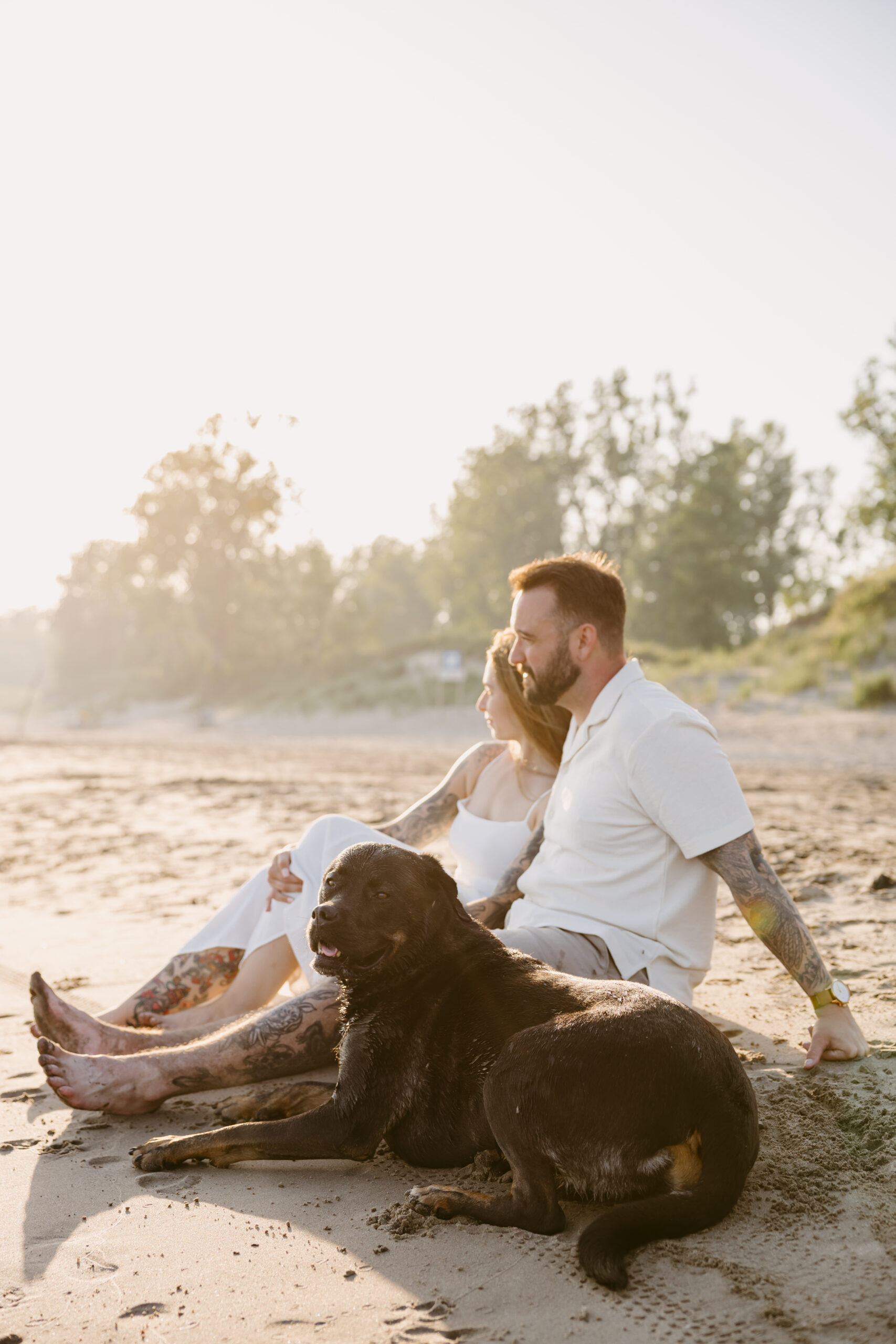 Couple running barefoot across Long Point Beach at sunset with their dog.