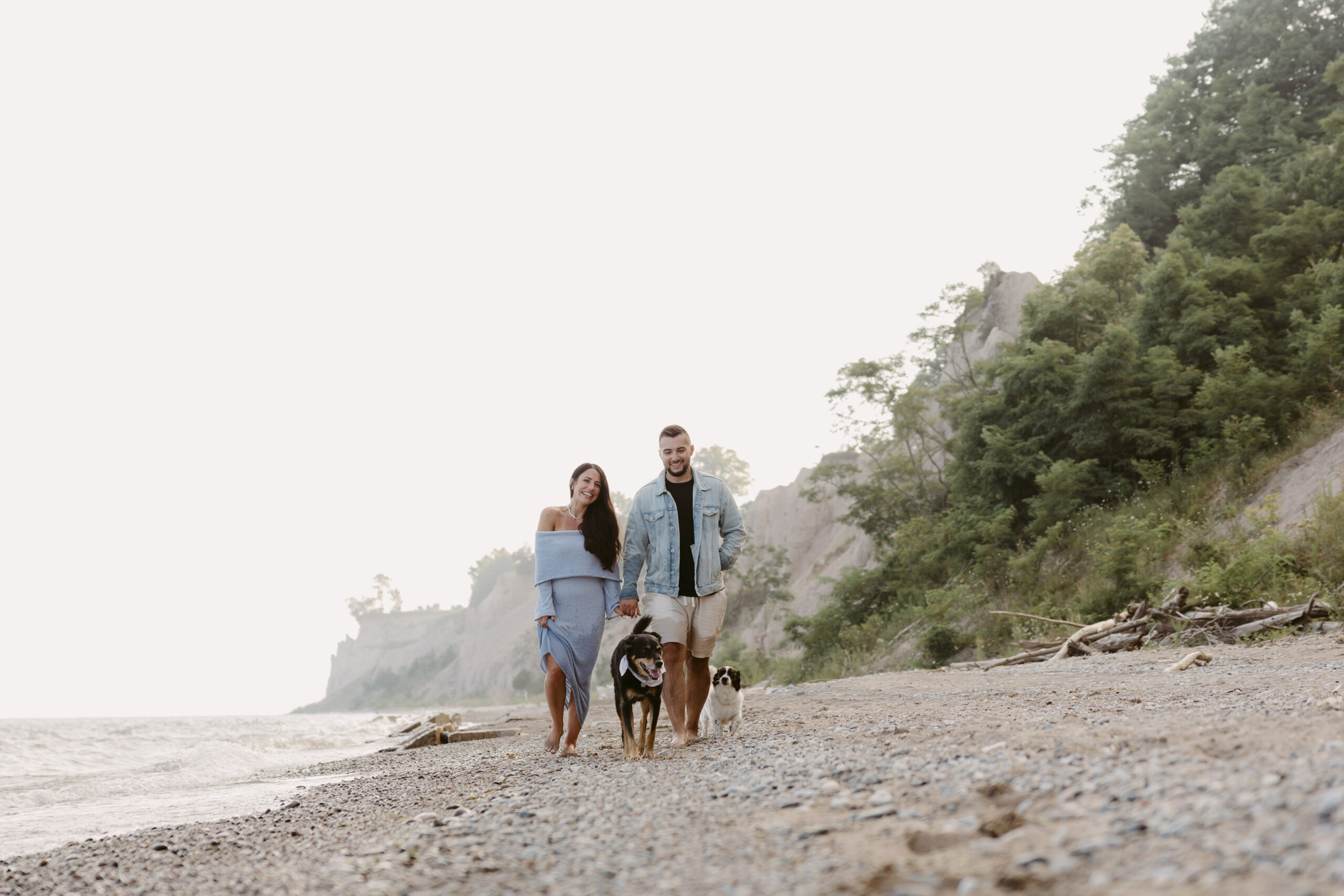 Couple walking along with beach with their 2 dogs.