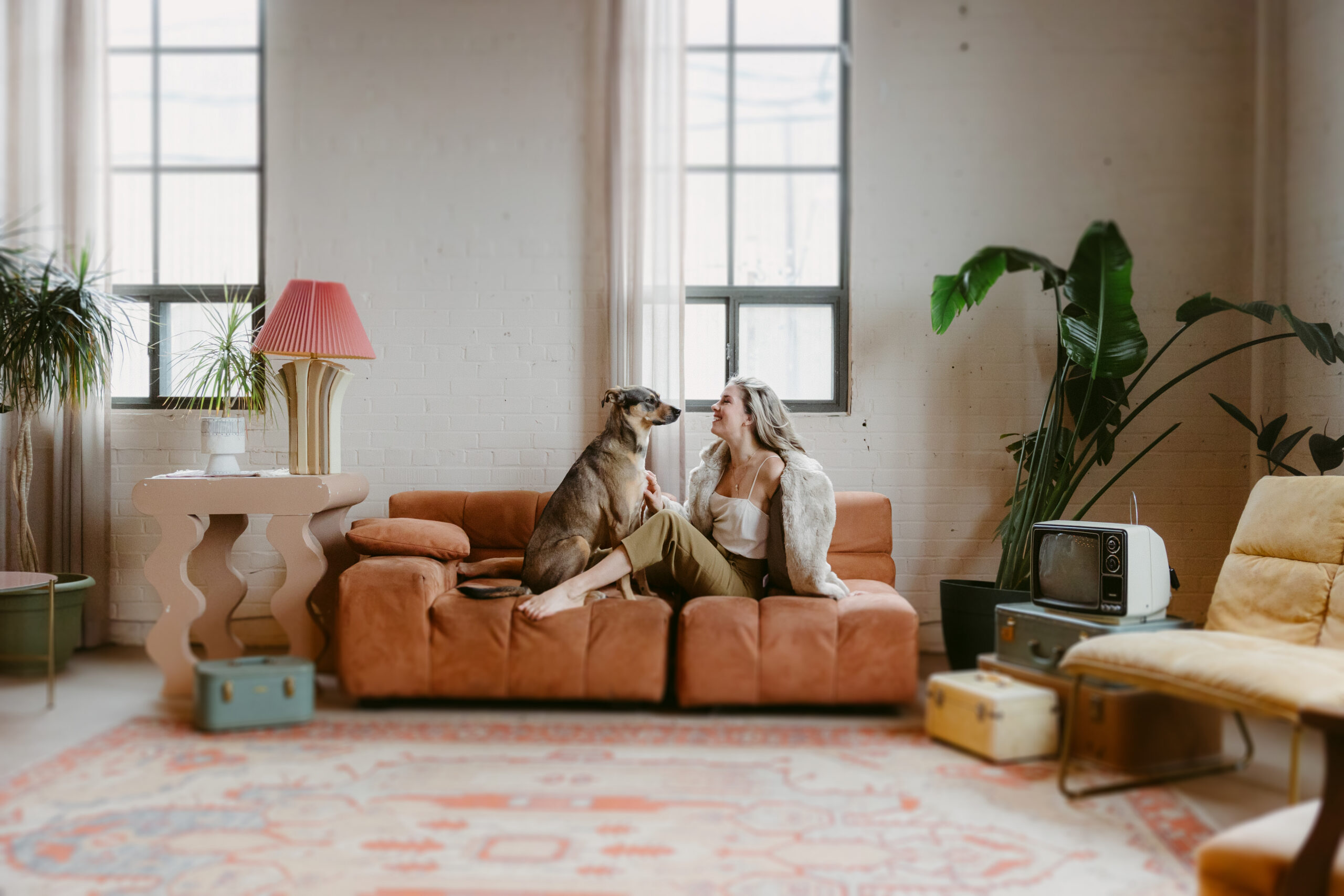 Women and dog on vintage couch looking at each other.